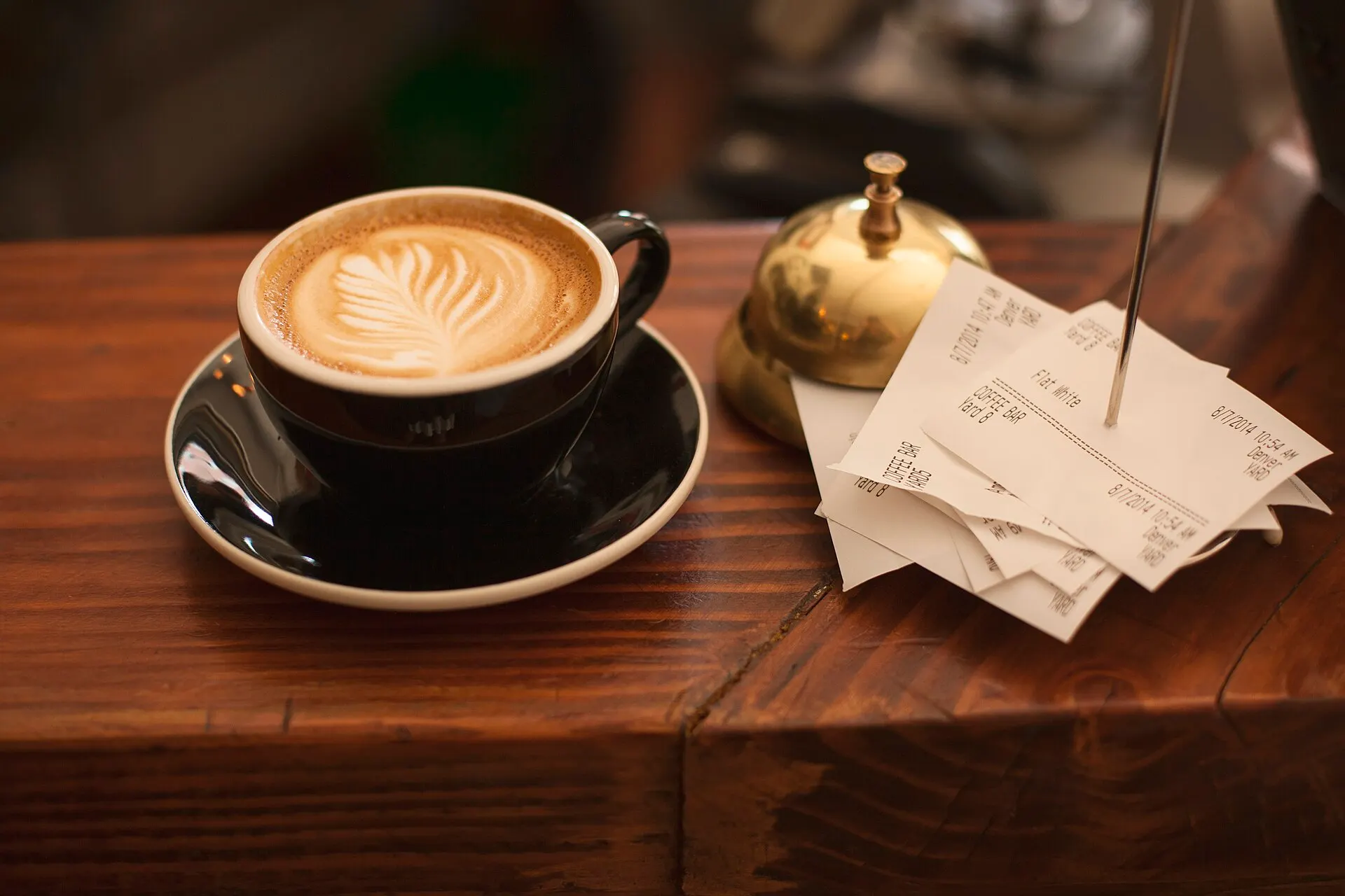 Symbolbild: Cappuccino mit Latte Art auf einem Holztresen im Café