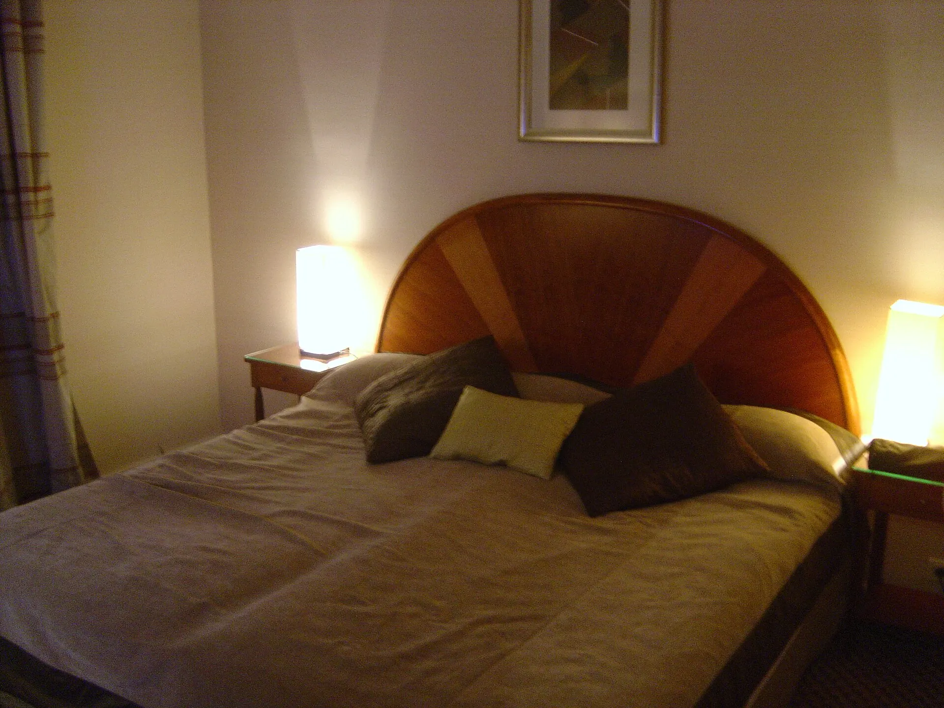 Symbolbild: Hotelzimmer mit bezogenem Doppelbett und warmer Nachttischbeleuchtung