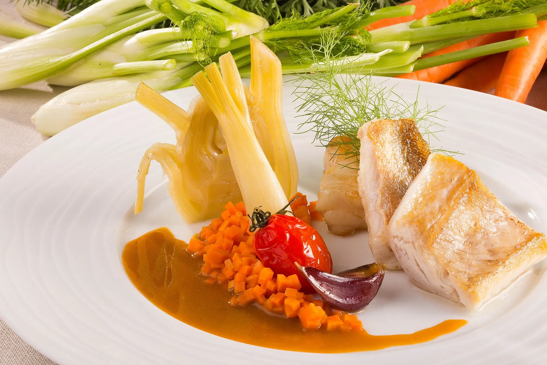 Symbolbild: Fein angerichtetes Fischgericht mit Gemüse und Sauce auf weißem Teller